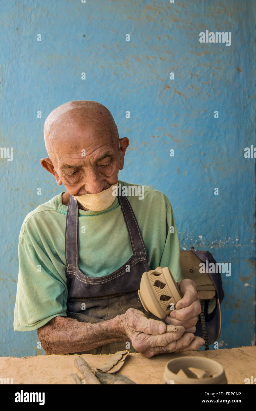 Un anziano artigiano cubano sands una candela titolare al Santander El Alfarero Casa Chichi workshop in Trinidad, Cuba. Foto Stock