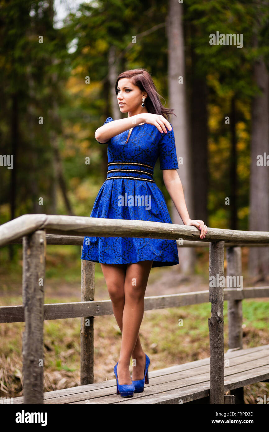 Bruna ragazza in vestito blu passeggiate al parco. Foto Stock