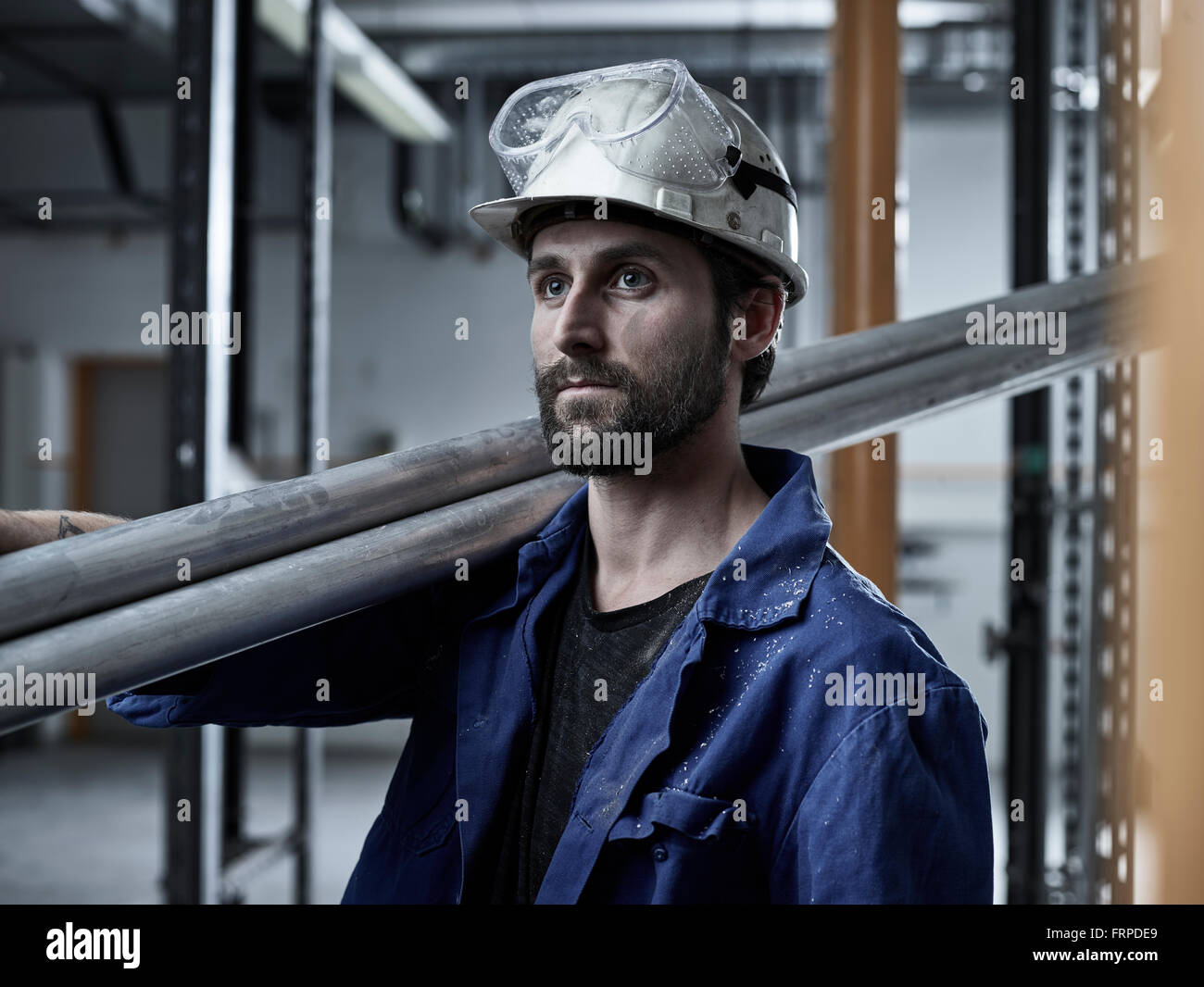 Lavoratore, meccanico con un casco e occhiali di sicurezza tubi portante sulla sua spalla, Austria Foto Stock