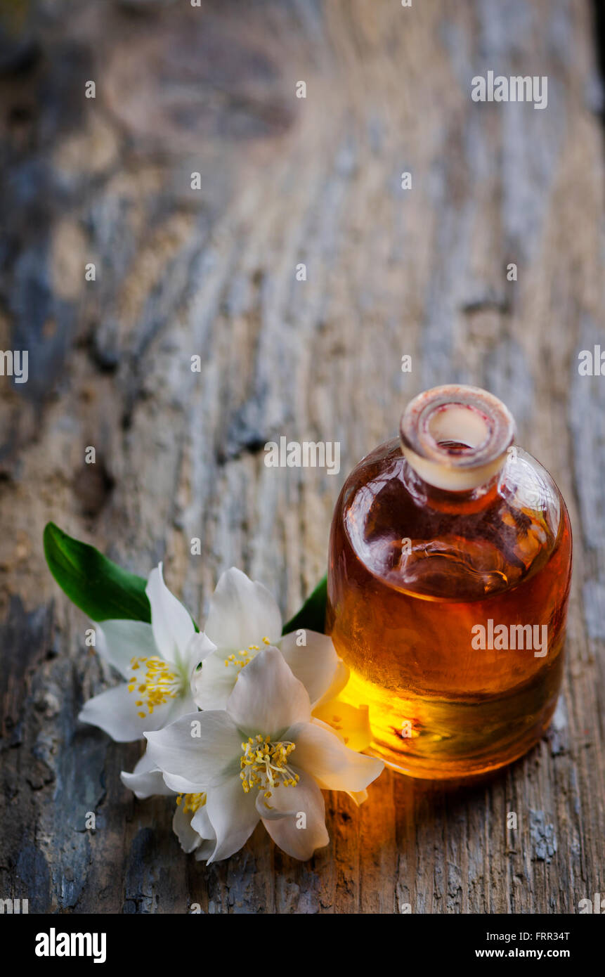 Concetto di aromaterapia. olio per massaggi e jasmin fiore su tavola in legno rustico. Foto Stock
