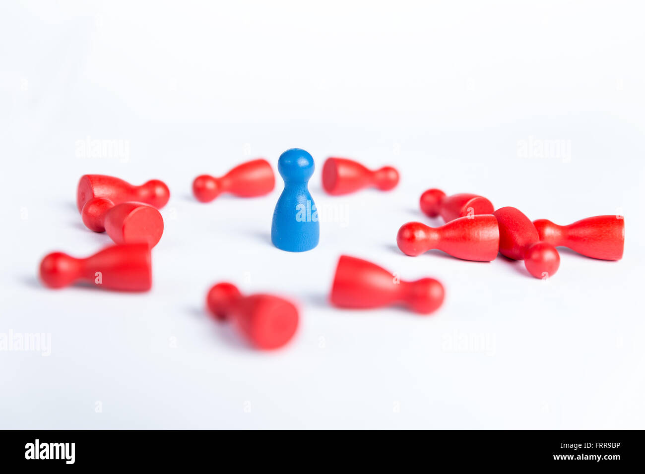 Figurina blu circondato da red pegni sdraiato sul pavimento. Batterli tutti i concept per la vincita su bianco Foto Stock
