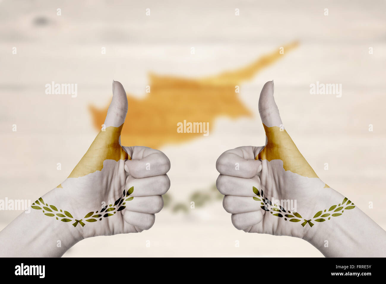 Bandiera di Cipro dipinta su mani femminili Thumbs up con sfocate sullo sfondo di legno Foto Stock