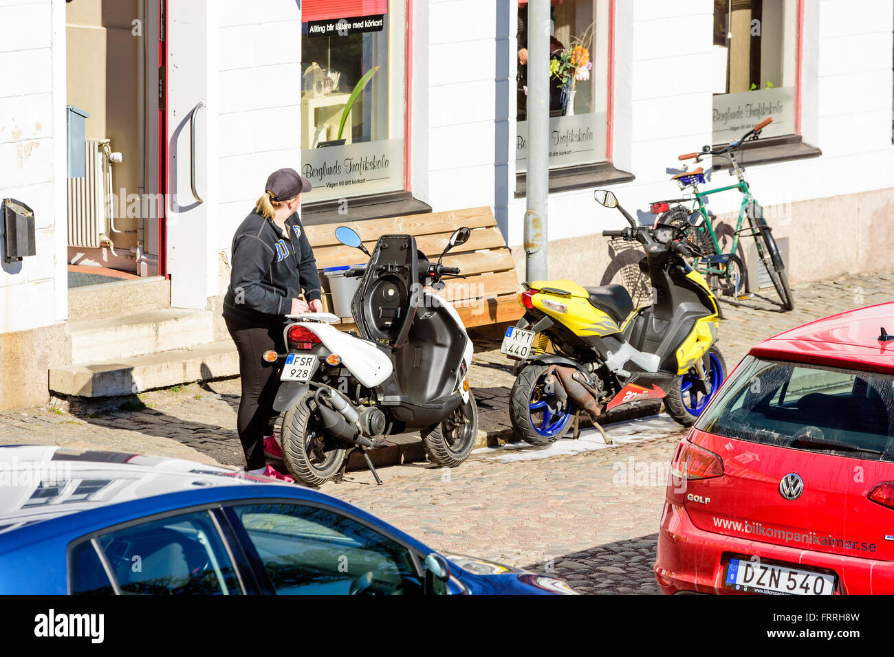 Kalmar, Svezia - 17 Marzo 2016: una giovane femmina adulta stare accanto a un ciclomotore al di fuori di una scuola guida. Ciclomotori sella è aperto e t Foto Stock