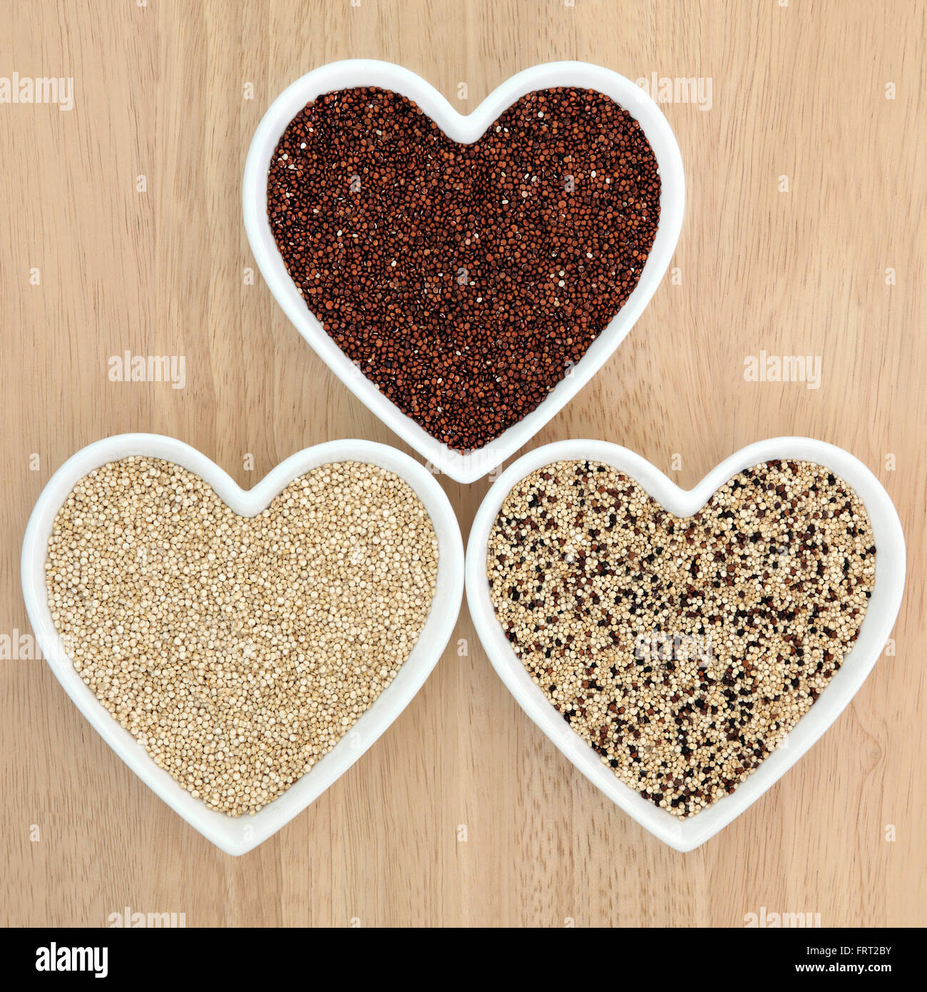 La quinoa health food varietà nel cuore a forma di tazze in porcellana con legno di faggio sfondo. Foto Stock