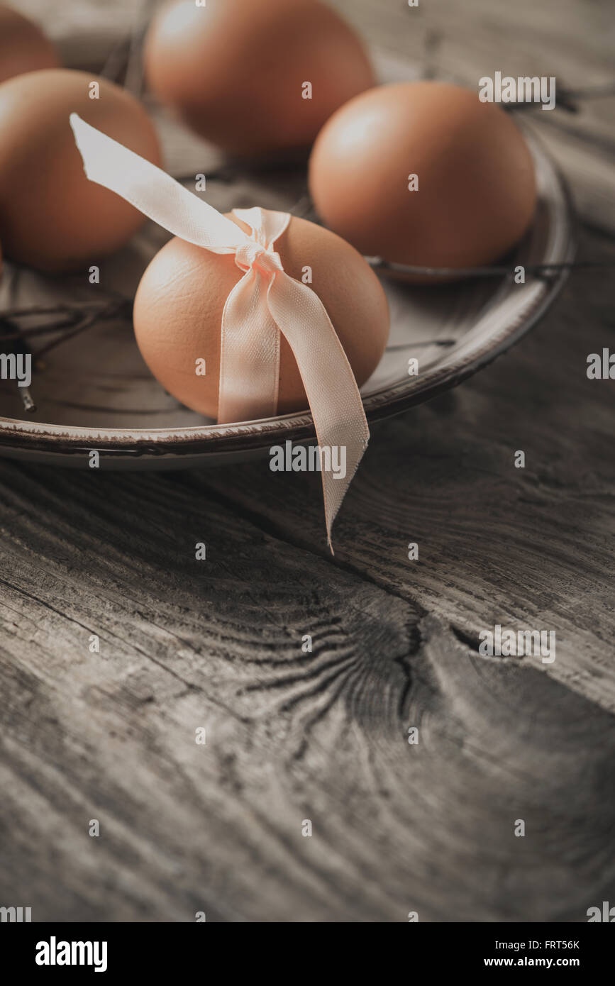 Uova con nastro e rami sul tavolo di legno in verticale Foto Stock