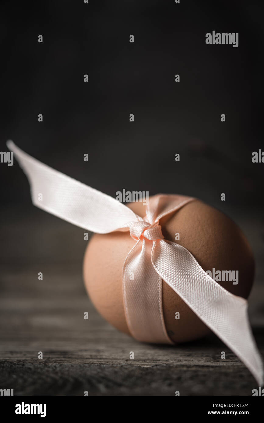 Uovo con nastro sul tavolo di legno Foto Stock