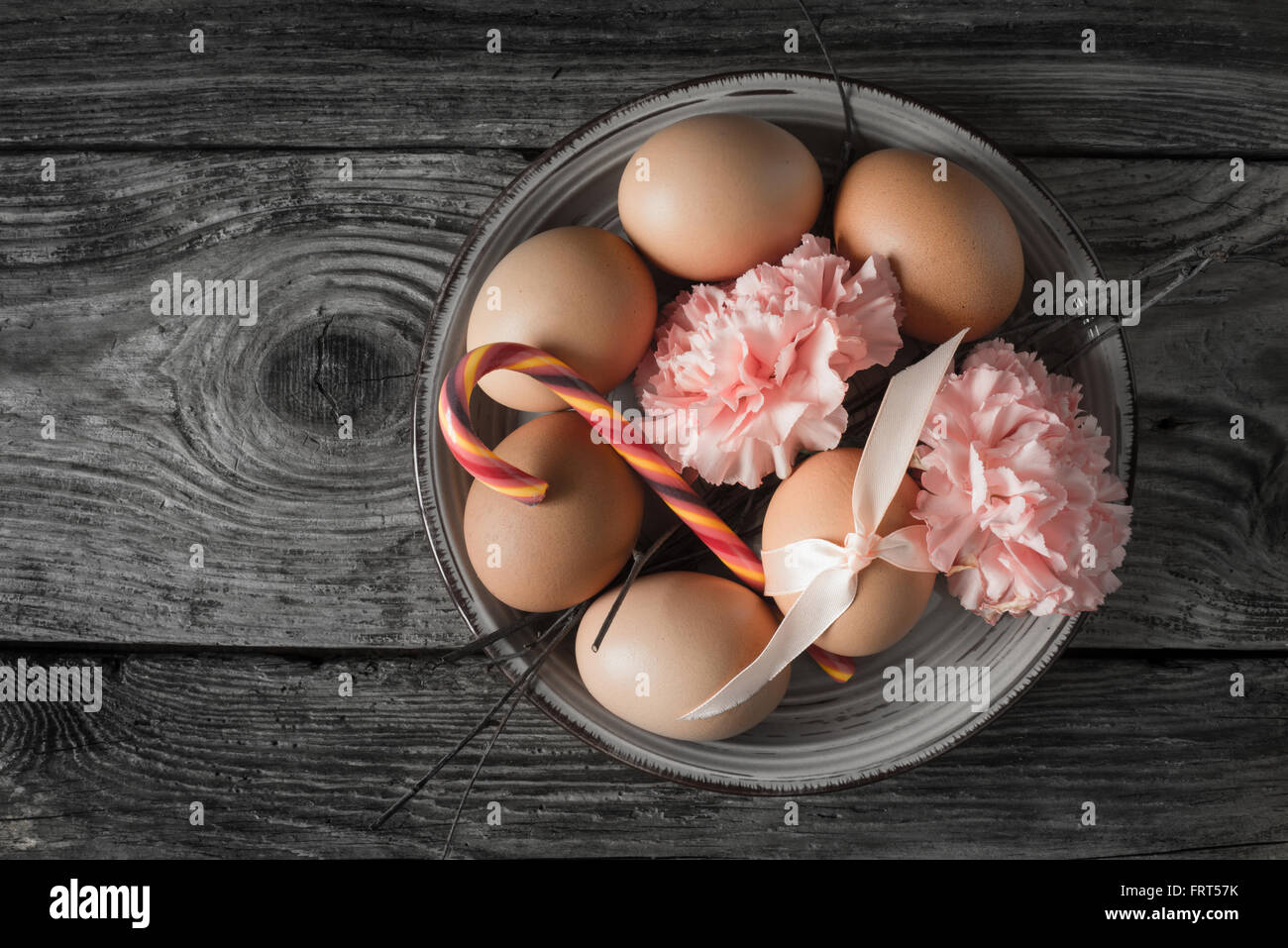 Uova con nastro , rami , fiori e caramelle sul tavolo di legno vista superiore Foto Stock