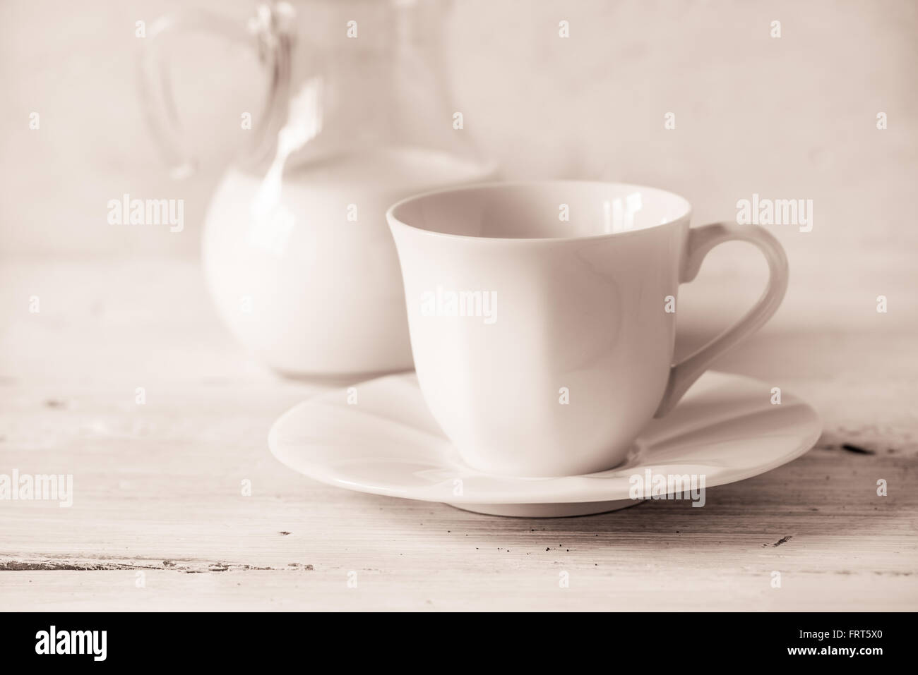Tazza da caffè con sfocato brocca del latte sul tavolo bianco Foto Stock