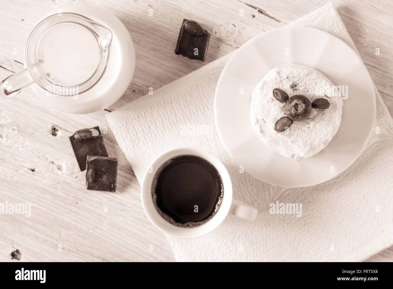 Tazza di caffè con la brocca del latte e torta di cioccolato sulla tavola bianco vista superiore Foto Stock