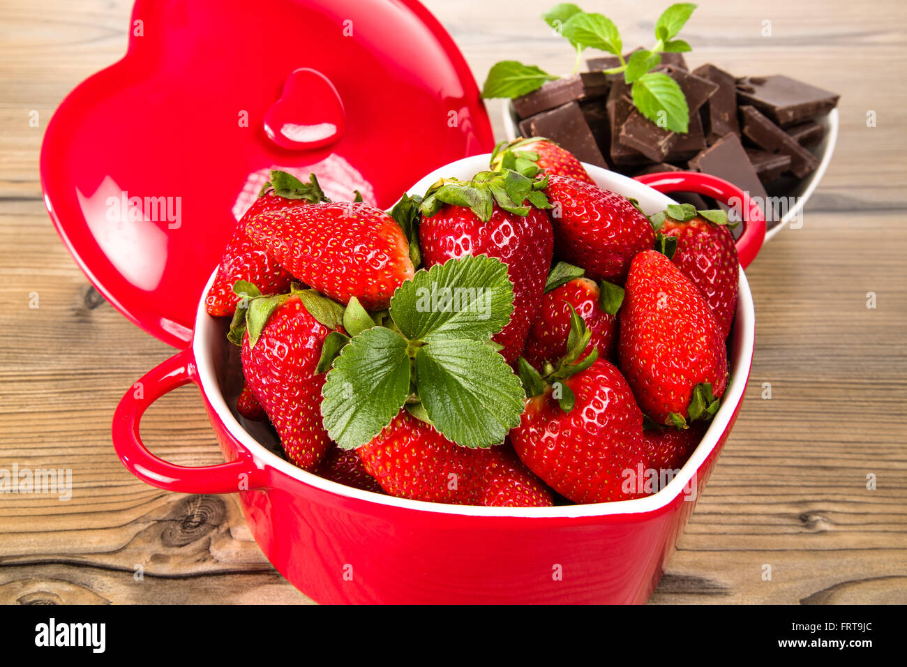 Le fragole in un recipiente di cuore, cioccolato e menta Foto Stock