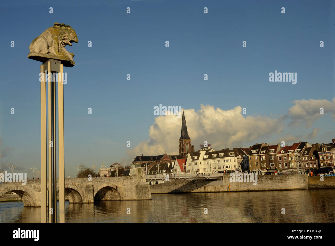 Piccolo lion sul piedistallo accanto al fiume Maas nel Trattato di Maastricht. Sint Servatius bridge e St Martins chiesa in background. Foto Stock