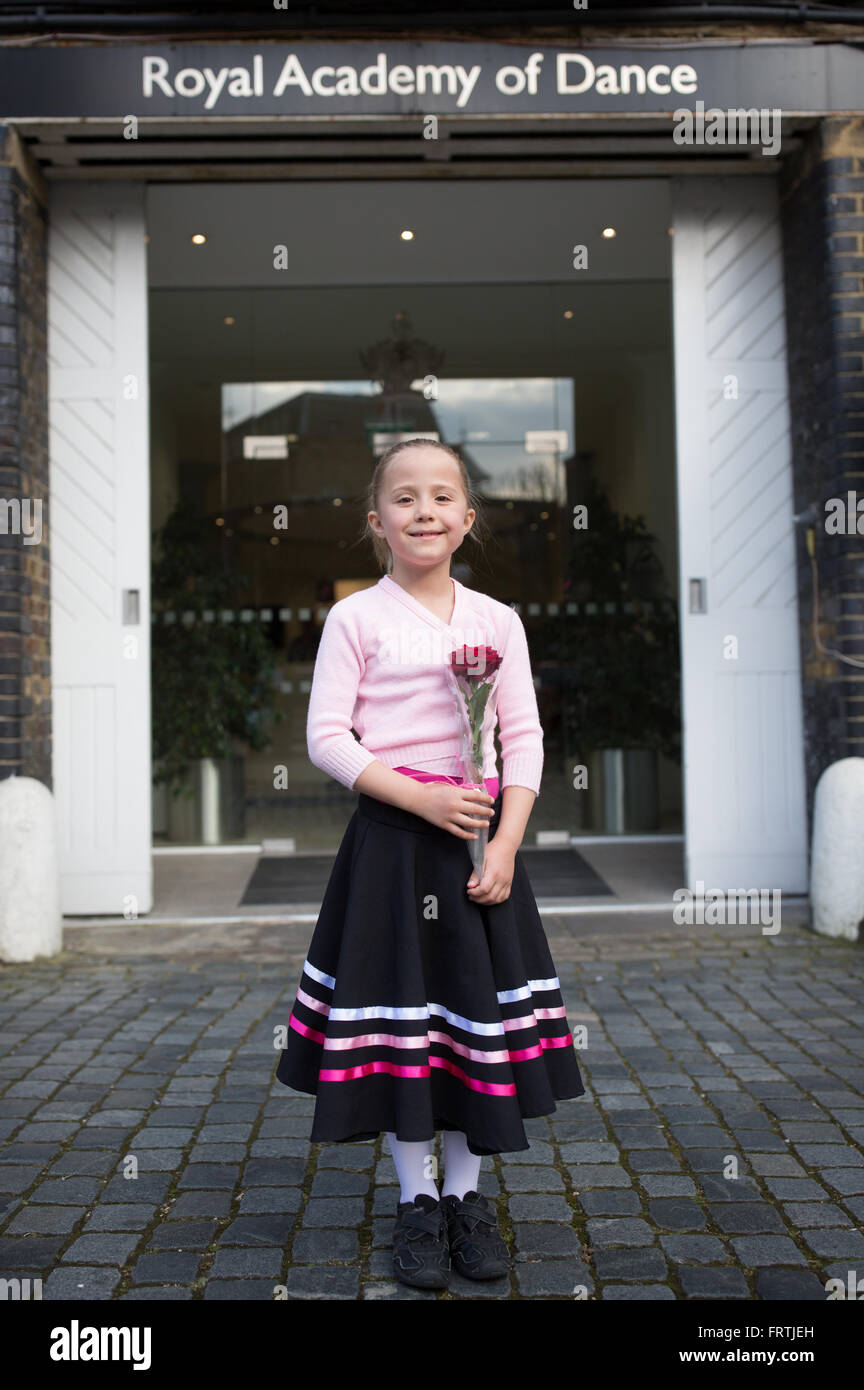 Una giovane ragazza pone con una rosa rossa a seguito del suo grado 1 esame di balletto al di fuori della Royal Academy of Dance di Londra Foto Stock