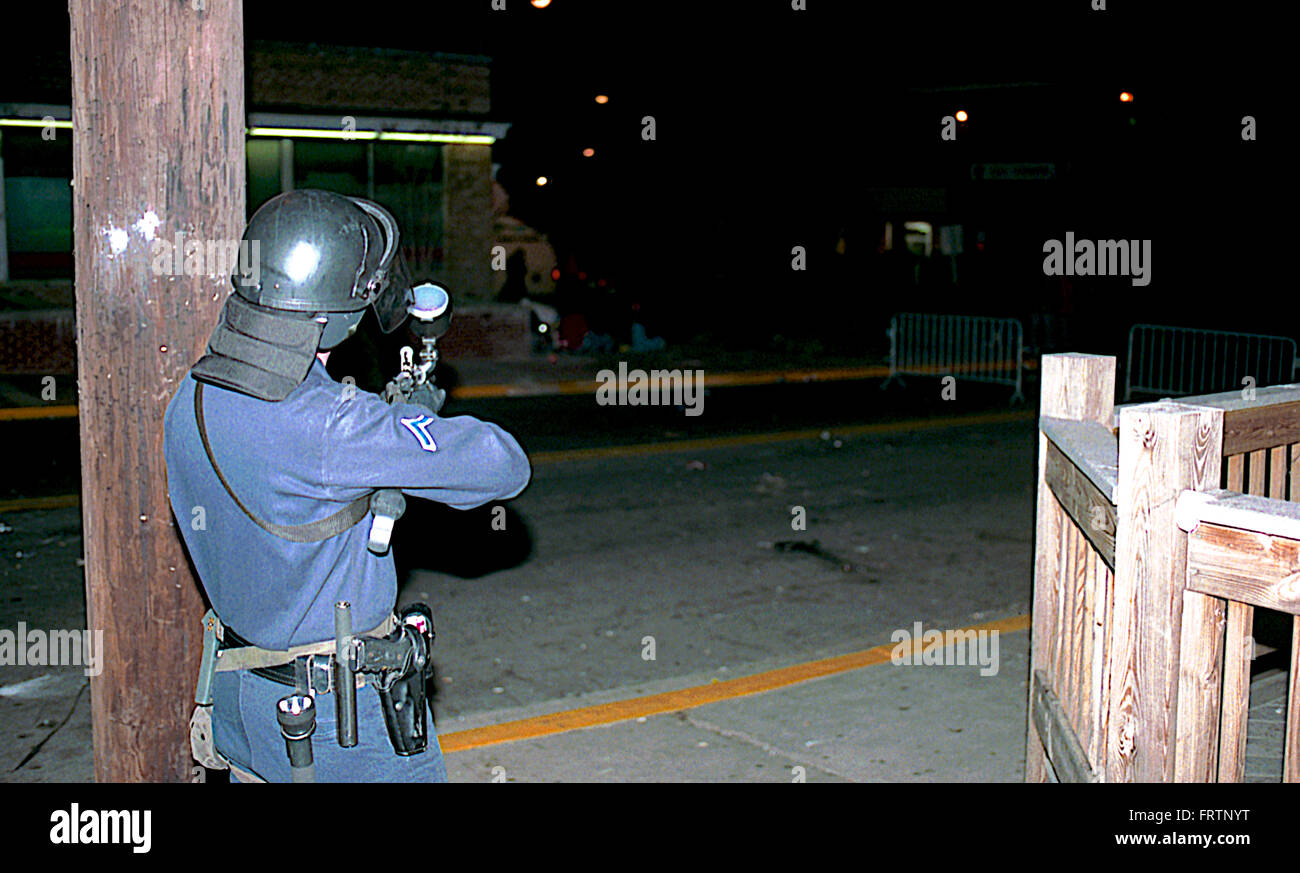 College Park, Maryland, USA, 1 Aprile, 2002 Prince George funzionario di polizia sparare una palla di vernice gas lacrimogeni pistola a studenti durante una sommossa che si è verificato dopo l'Università del Maryland sconfitto Indiana la rivendicazione del titolo alla NCAA di pallacanestro degli uomini di campionato. È stato Maryland il primo college basketball titolo e la vittoria di ventole inviato in una frenesia. Una stima di 5.000 ha colpito le strade nella celebrazione. Alimentato da un consumo eccessivo di alcol, il mob accesa nei bidoni della spazzatura e divani sul fuoco e iniziato il ribaltamento degli oggetti in strada. 6 auto della polizia sono state danneggiate, incendi sono stati impostati. Credito: Mark Reinstein Foto Stock