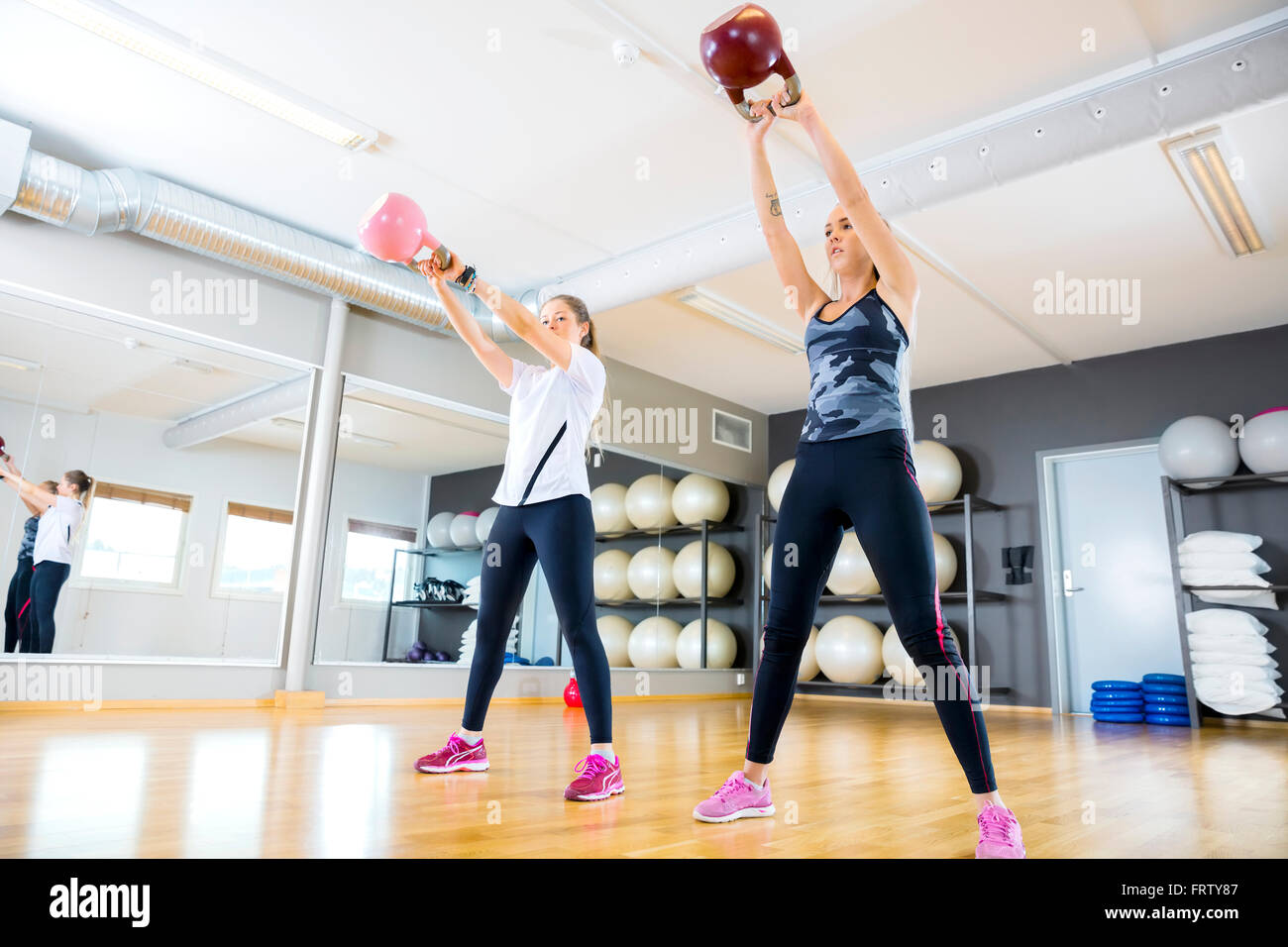 Due donne treni con kettlebells in palestra per il fitness Foto Stock