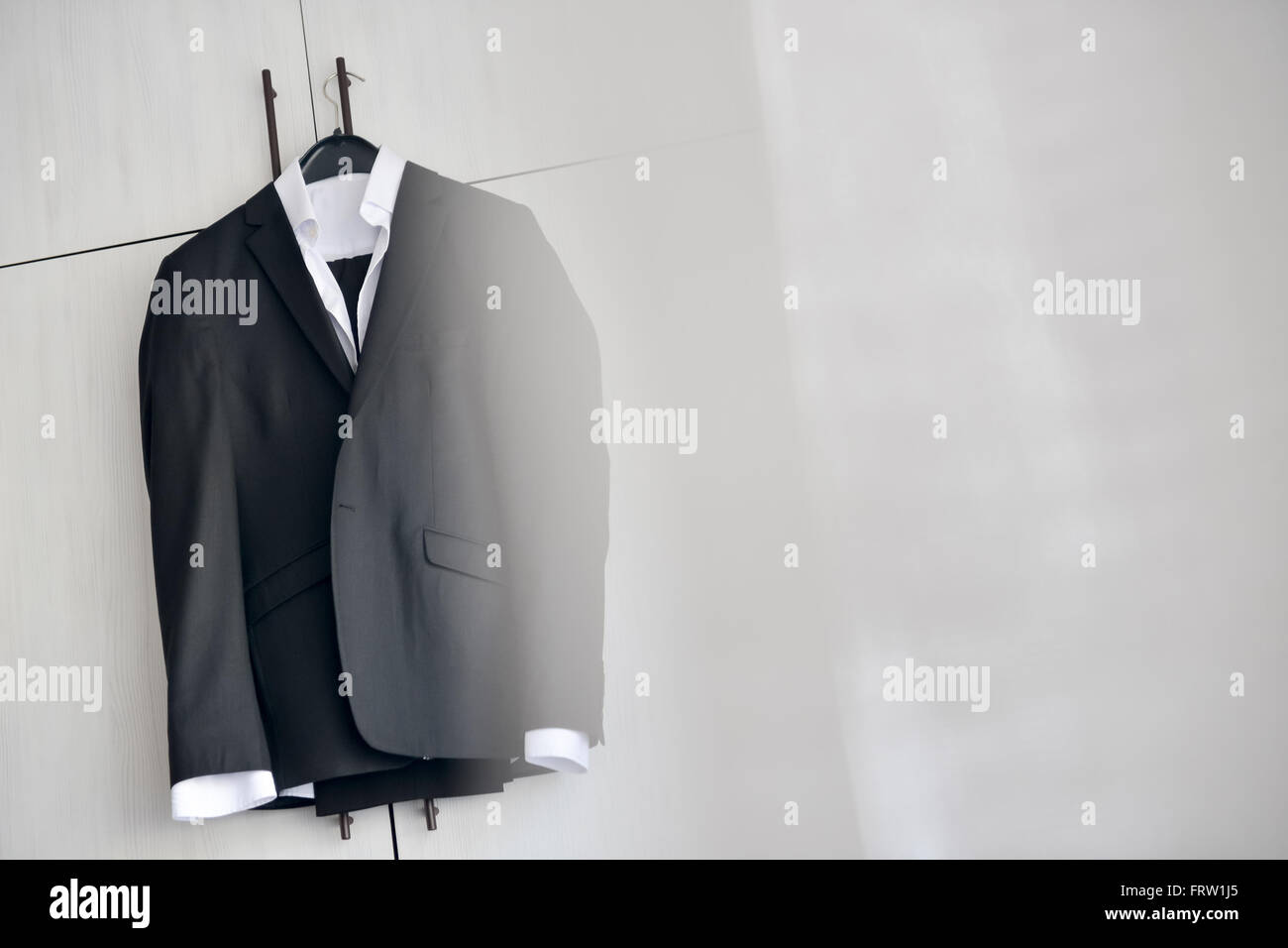 Abito nero appeso ad un armadio in legno nella luce naturale Foto Stock