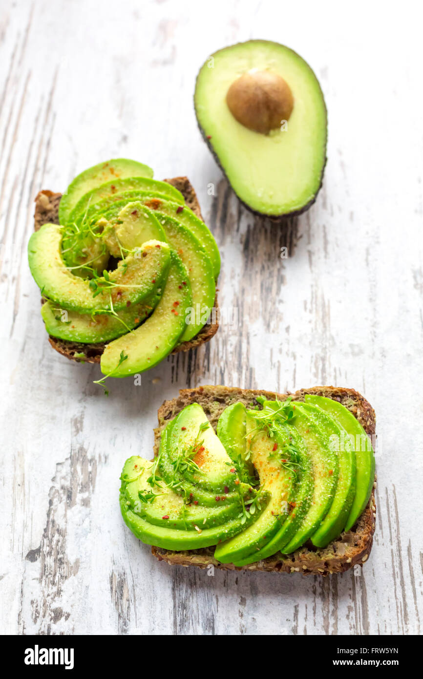 Pane di proteina guarnite con fette di avocado, il crescione e il peperoncino in polvere Foto Stock