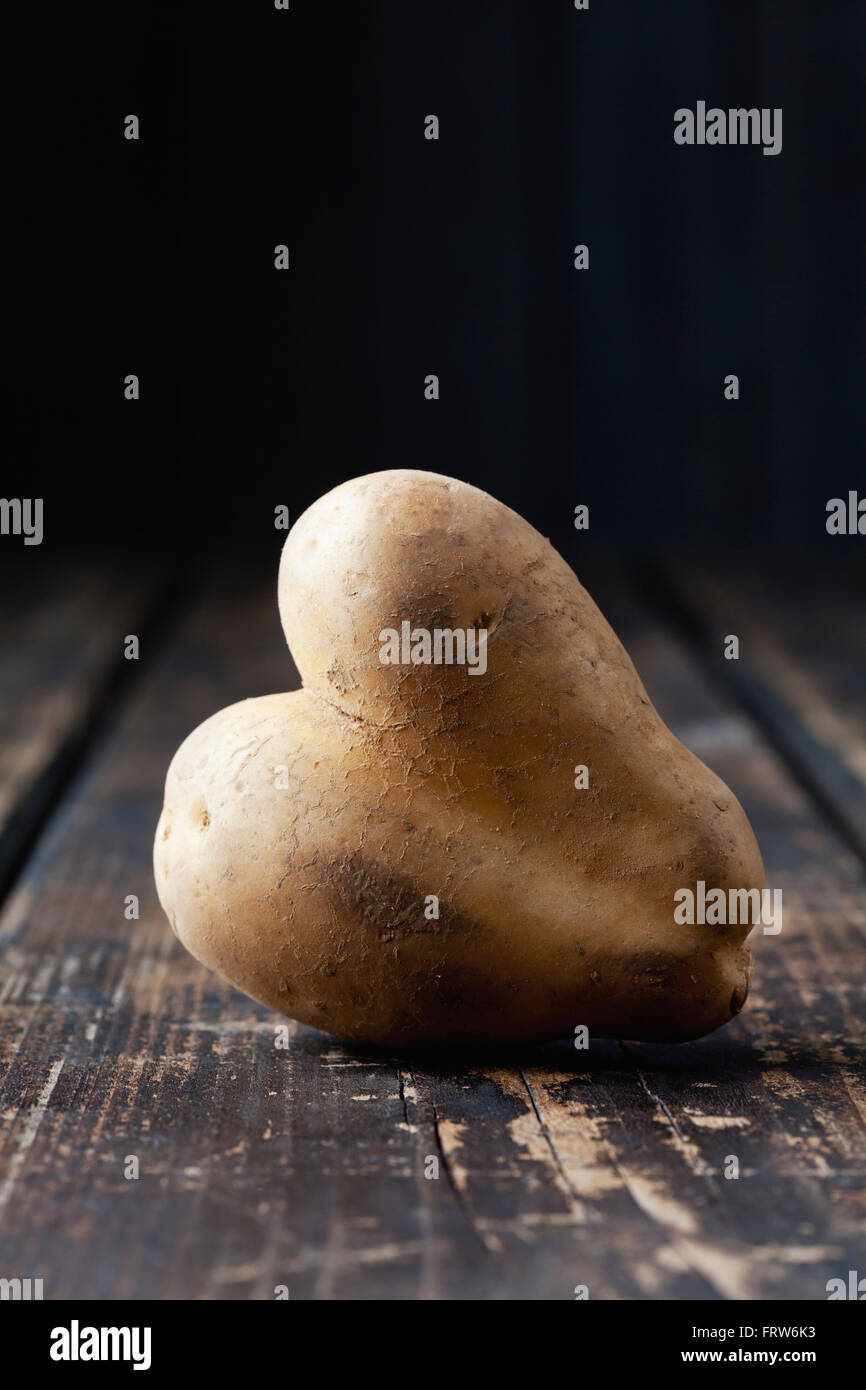 A forma di cuore sulla patata legno scuro Foto Stock