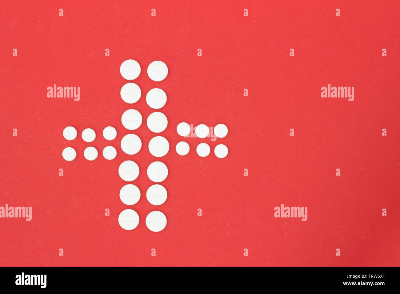 Forma a croce delle compresse di colore bianco sulla terra rossa Foto Stock