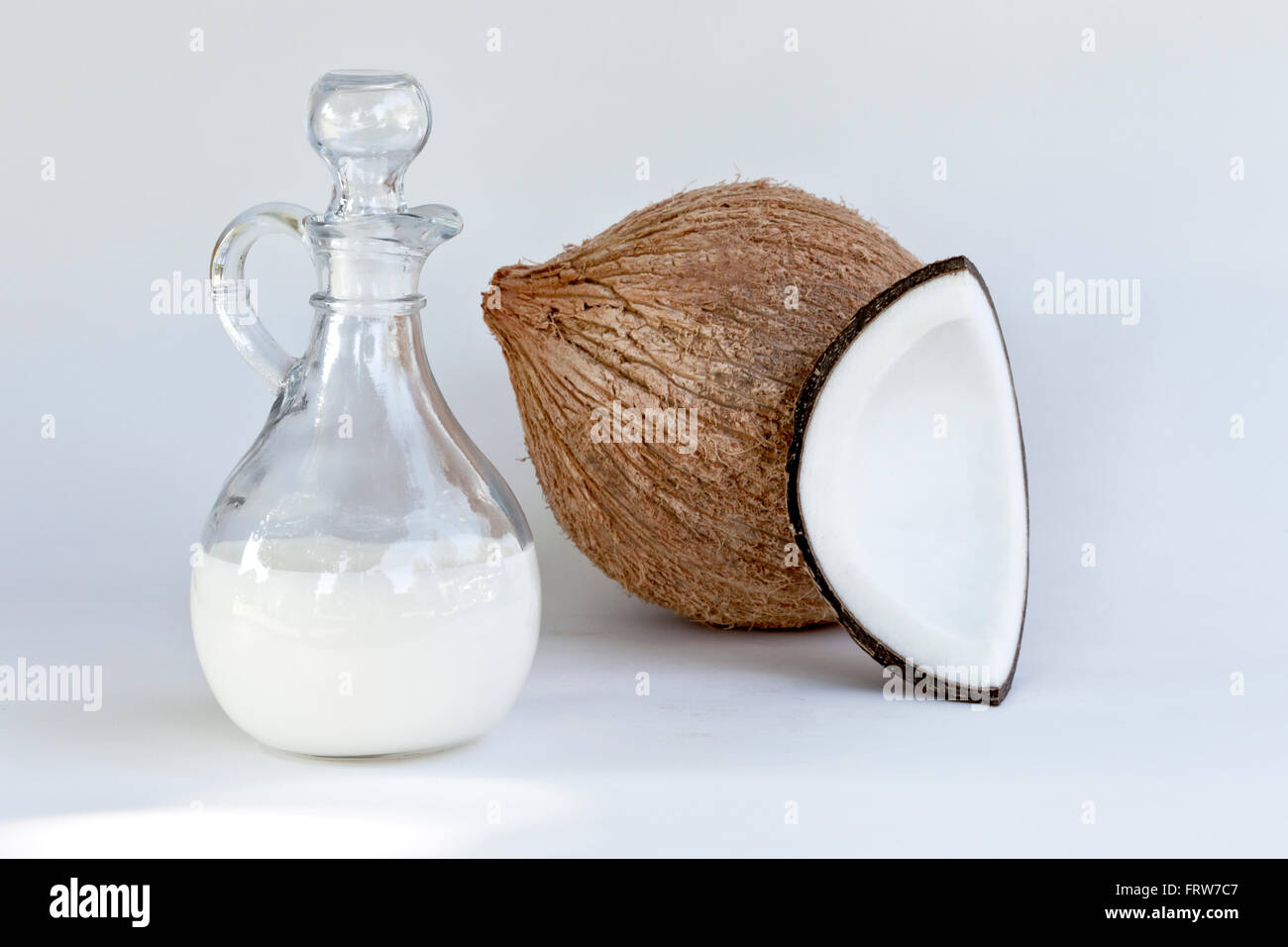 Semi solido olio di noce di cocco nella caraffa di vetro, interi & quartered dado. Foto Stock