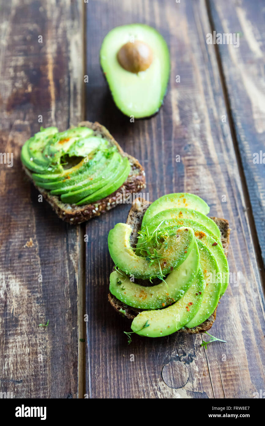 Pane di proteina guarnite con fette di avocado, il crescione e il peperoncino in polvere Foto Stock