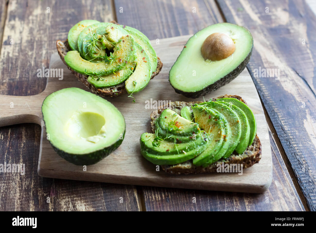 Pane di proteina guarnite con fette di avocado, il crescione e il peperoncino in polvere Foto Stock
