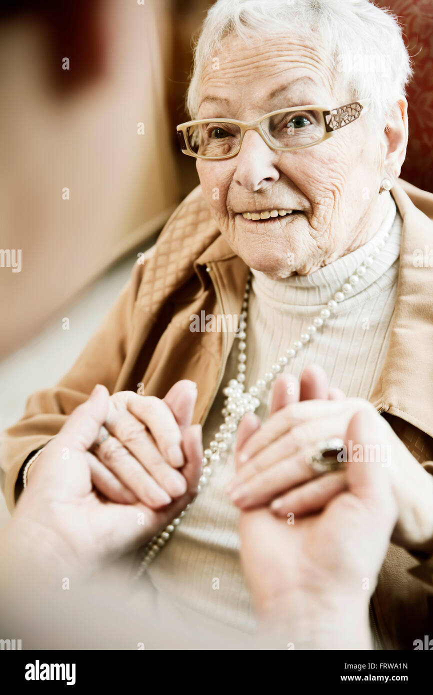 Ritratto di donna senior con il morbo di Alzheimer tenendo le mani di sua figlia adulta Foto Stock