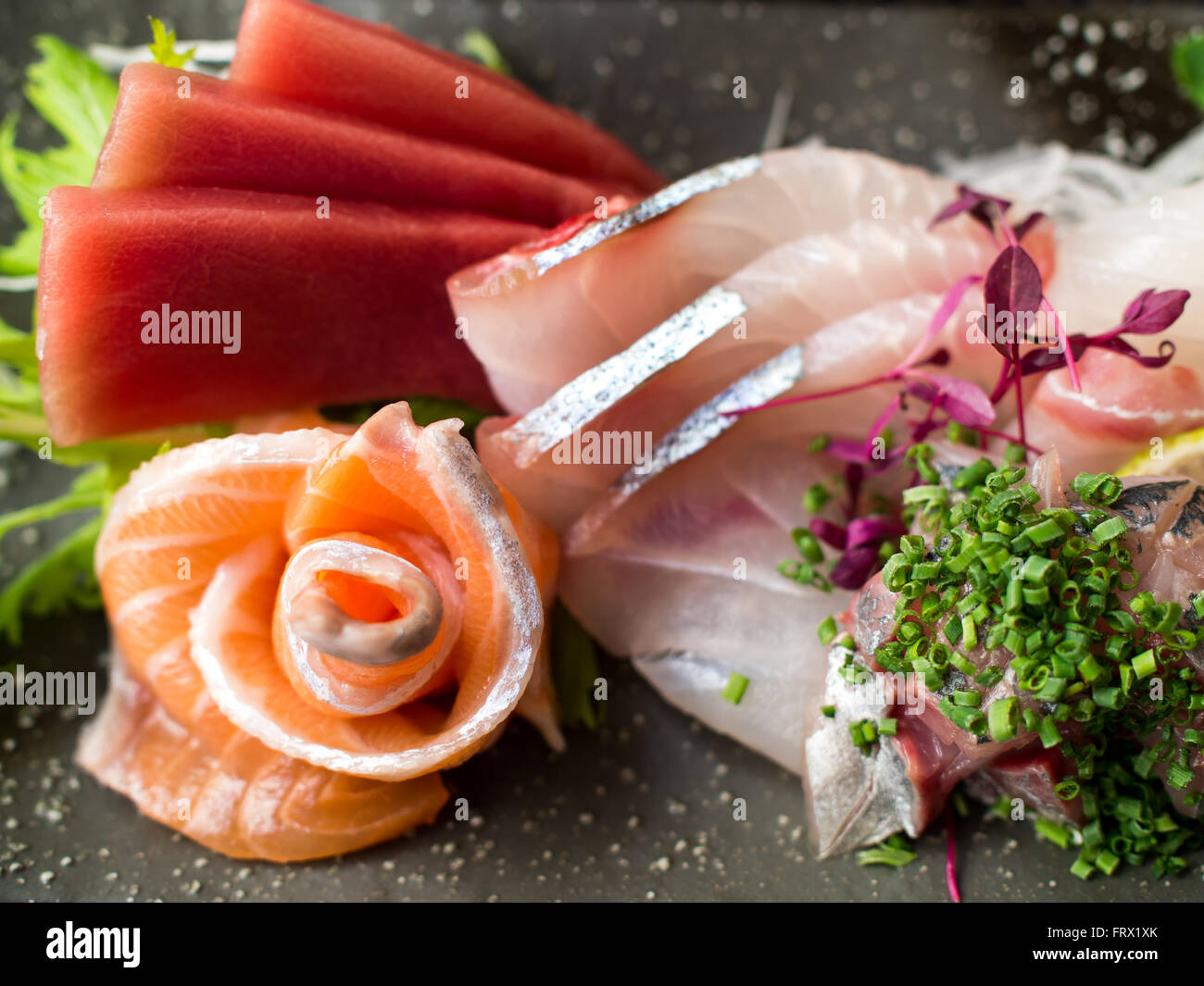 Giapponese pesce crudo sulla piastra nera. Noto anche come il sashimi. Foto Stock