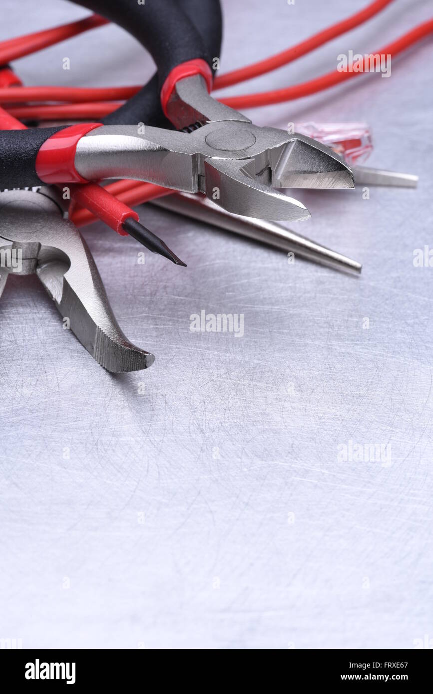 Strumenti per elettricista e i cavi grigio sulla superficie metallica Foto Stock