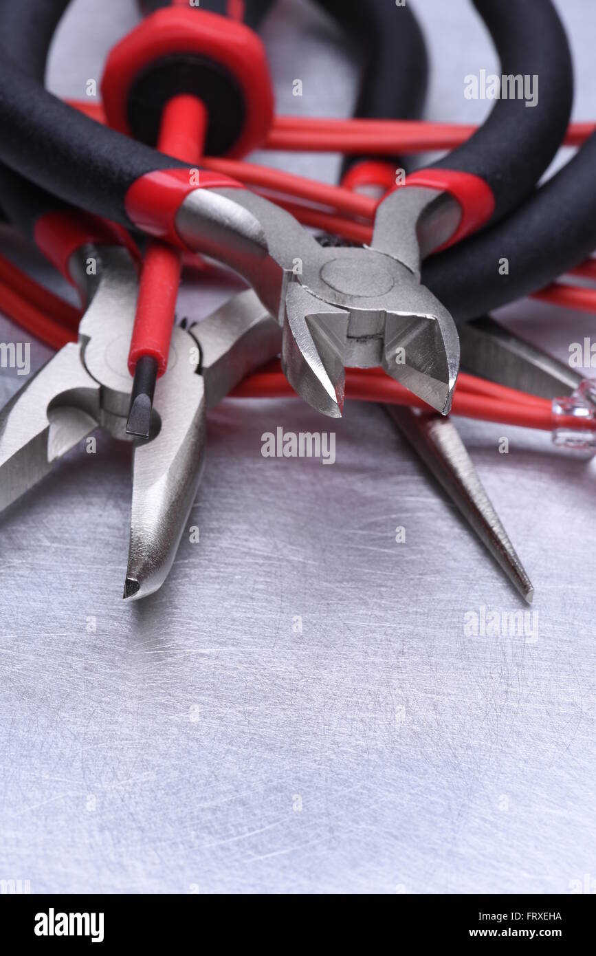 Strumenti per elettricista e i cavi grigio sulla superficie metallica Foto Stock