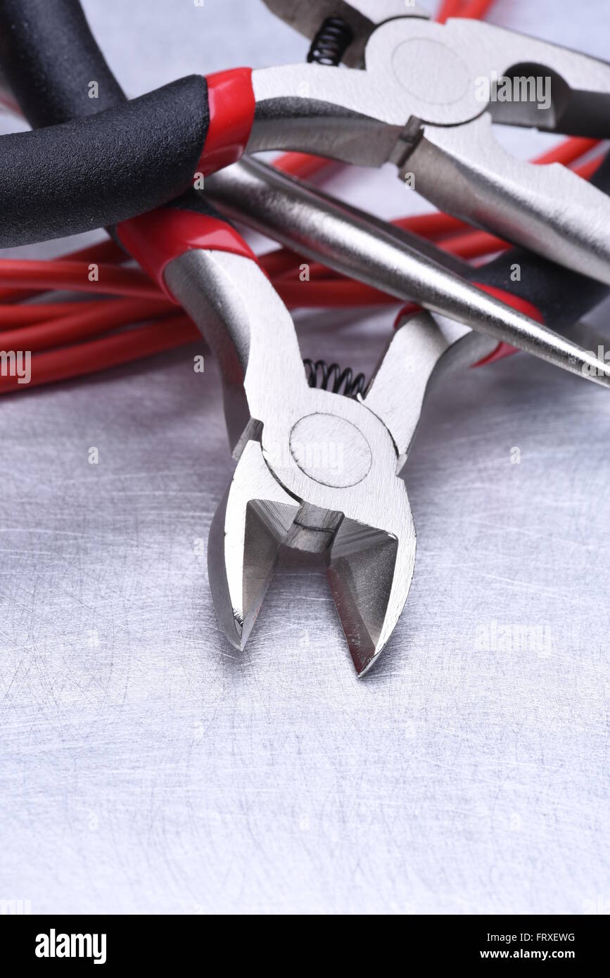 Strumenti per elettricista e i cavi grigio sulla superficie metallica Foto Stock
