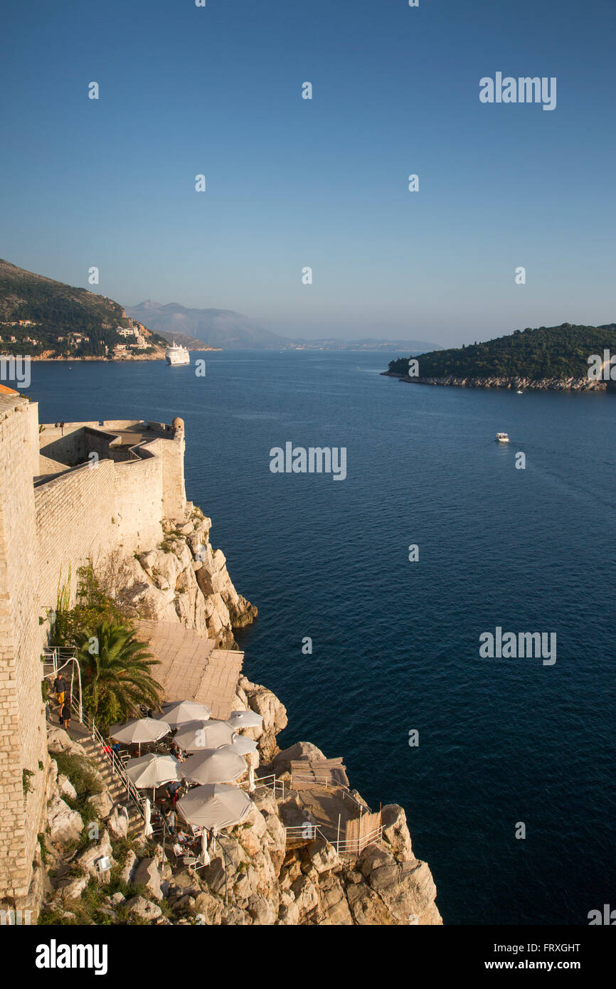 Ombrelloni presso una caffetteria che si affaccia sulla costa sotto le mura della città vecchia, Dubrovnik, Dubrovnik-Neretva, Croazia Foto Stock