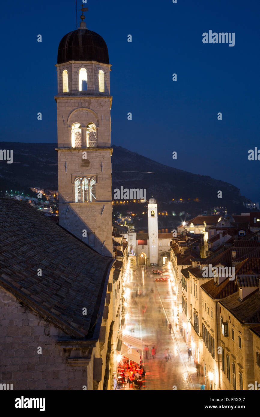 Pedoni nella città vecchia di Placa con chiesa francescana Torre del monastero visto dalla parete della città di notte, Dubrovnik, Dubrovnik-Neretva, Croazia Foto Stock