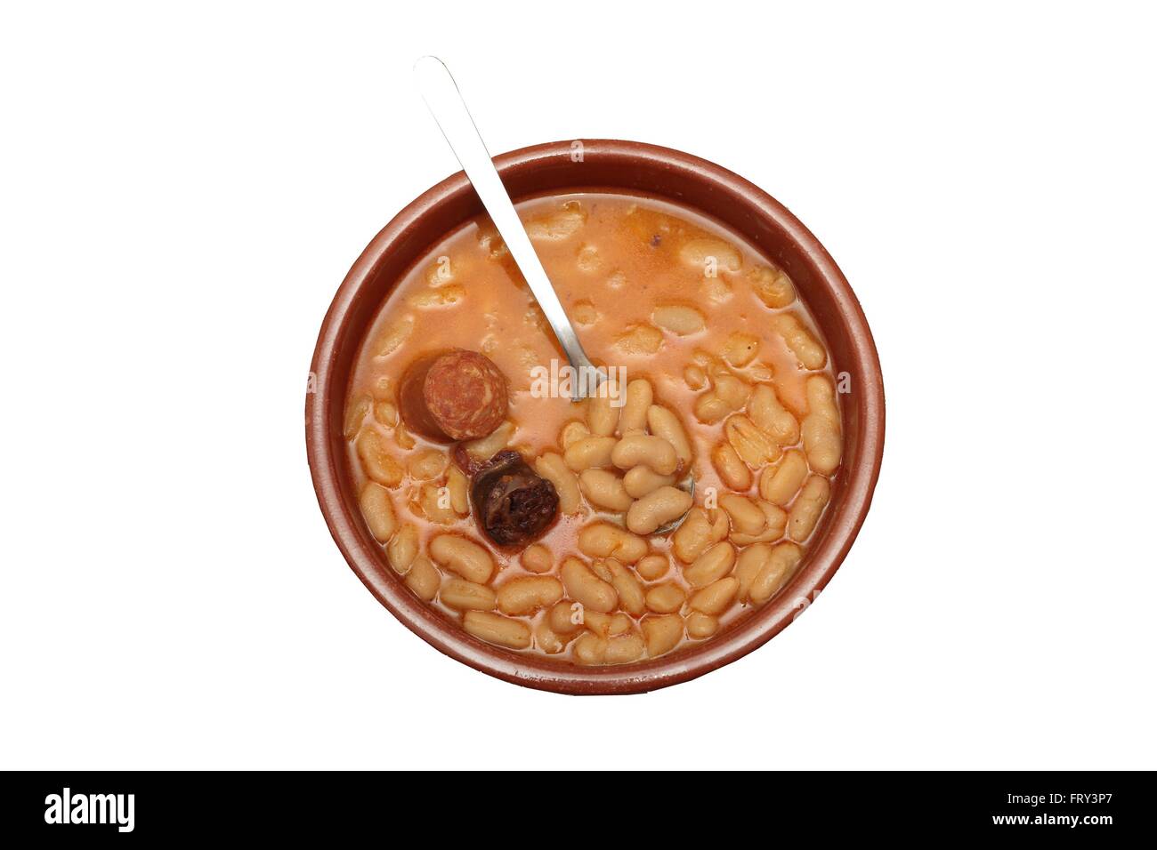 Asturiano stufato di fagioli in una pentola di creta su uno sfondo di legno vecchio Foto Stock