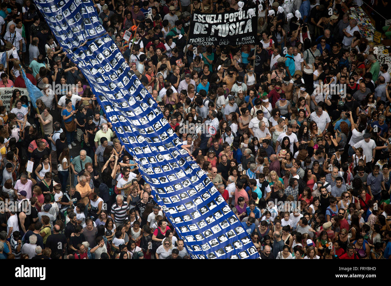Buenos Aires, Argentina. 24 Mar, 2016. Le persone in possesso di un enorme striscione con le facce degli scomparsi durante la dittatura militare, nel mese di marzo per i 40 anni del colpo di stato del 1976, nella città di Buenos Aires, capitale dell'Argentina, il 24 marzo 2016. Il colpo di stato è stato tenuto il 24 marzo 1976, e rovesciò quindi Argentina del Presidente Maria Estela Martinez de Peron per stabilire una pensione militare guidato da Jorge Rafael Videla. Diversi ambiti sociali, politici e organizzazioni degli studenti hanno preso parte nel mese di marzo per commemorare la Giornata Nazionale della memoria per la verità e la giustizia. Credito: Martin Zabala/Xinhua/Alamy Live Foto Stock