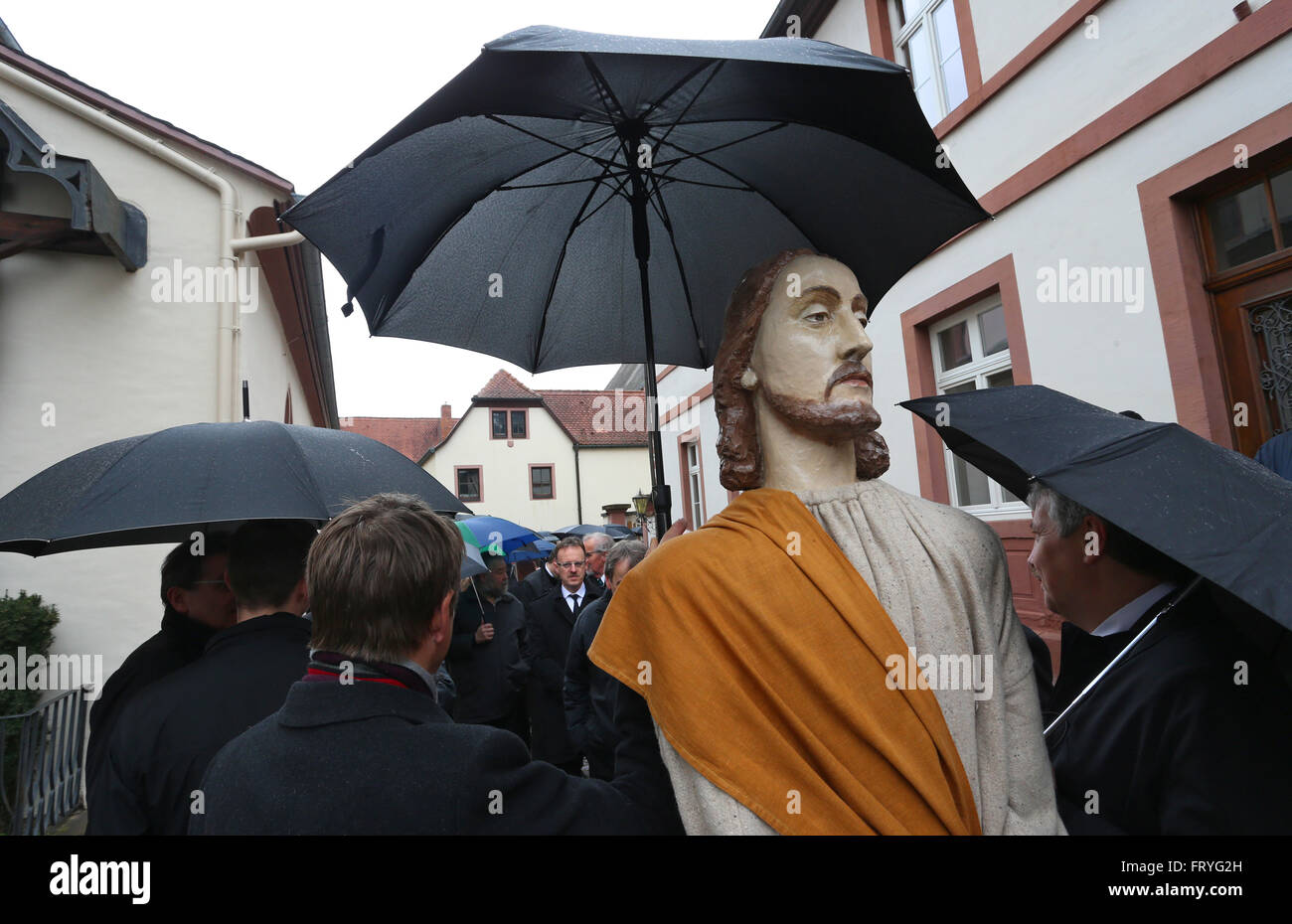 Lohr am Main, Germania, 25 marzo 2016. I membri delle varie Gilde a protezione di una figura di Gesù con un ombrello da pioggia a una processione del Venerdì santo attraverso il centro della città di Lohr am Main, Germania, 25 marzo 2016. Tredici life-size figure che rappresentano la passione di Cristo sono trasportate attraverso la città nella tradizionale processione. Credito: dpa picture alliance/Alamy Live News Foto Stock