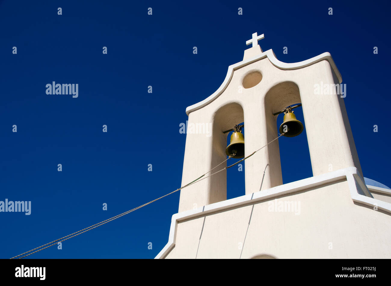 Funi collegate alle campane di una torre campanaria di fronte al cielo blu di una chiesa in Grecia Santorini Foto Stock