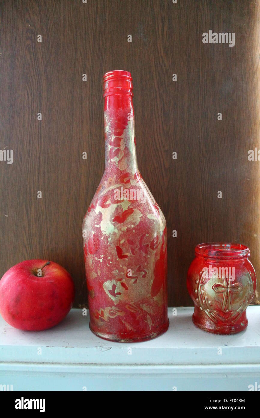 Decorazione per la casa realizzata dalla bottiglia di vetro dipinto in rosso e oro con i dolci di mela rossa Foto Stock