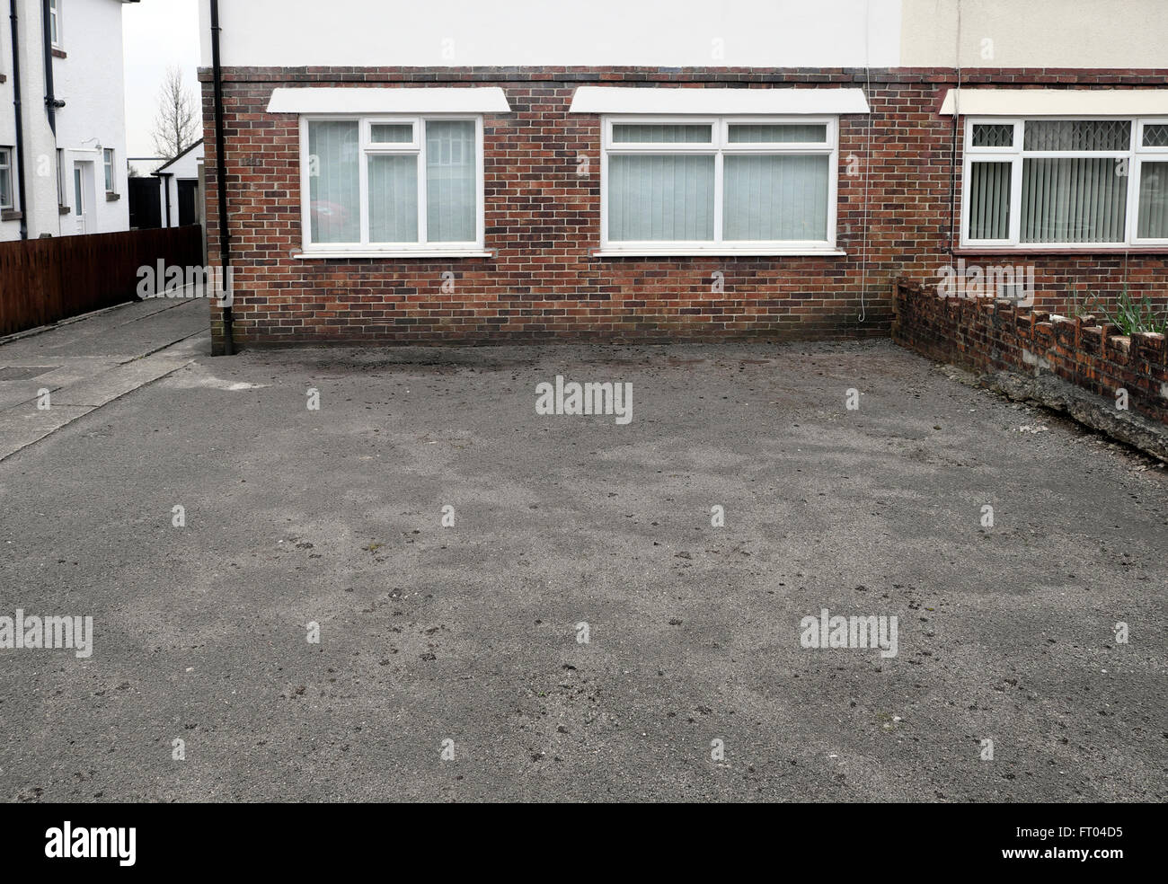 Un asfalto pavimentazione in giardino anteriore e area parcheggio per auto che colpiscono il drenaggio delle acque al di fuori di un Appartamento casa in Galles UK KATHY DEWITT Foto Stock