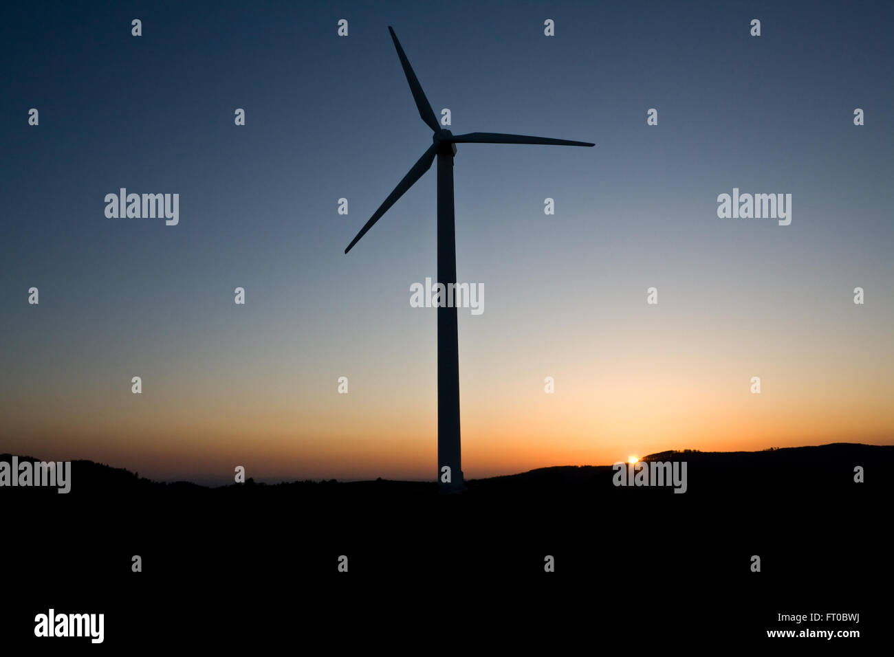Turbina eolica al tramonto con il rosso e il blu del cielo Foto Stock