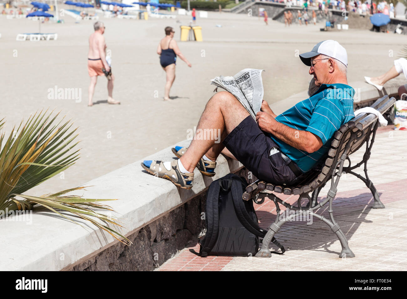 Uomo in pensione leggendo il giornale in spiaggia Foto Stock
