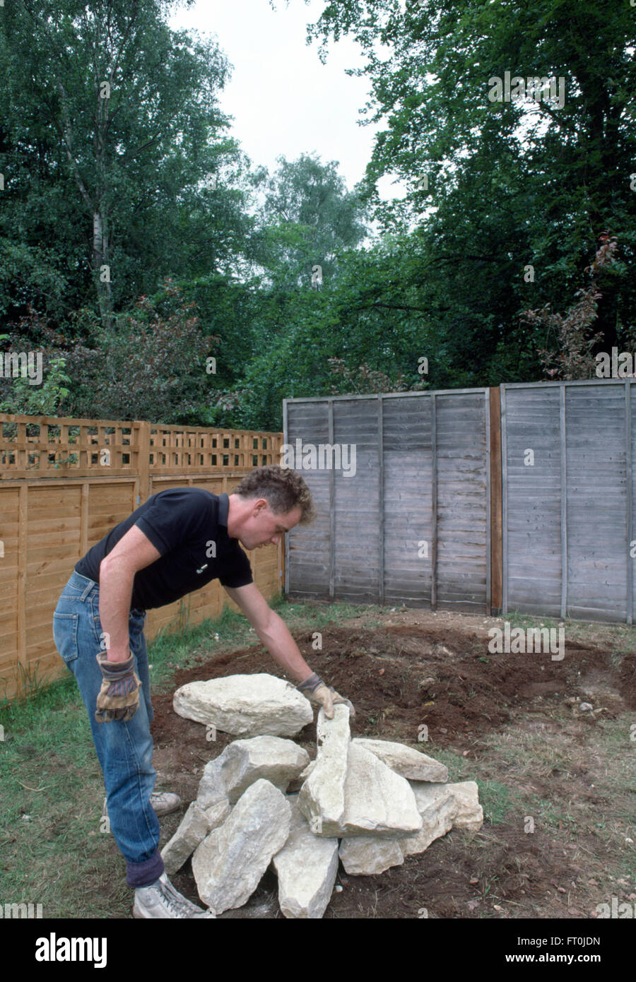 Giardiniere selezionando una roccia a posto in un nuovo rockery per solo uso editoriale Foto Stock