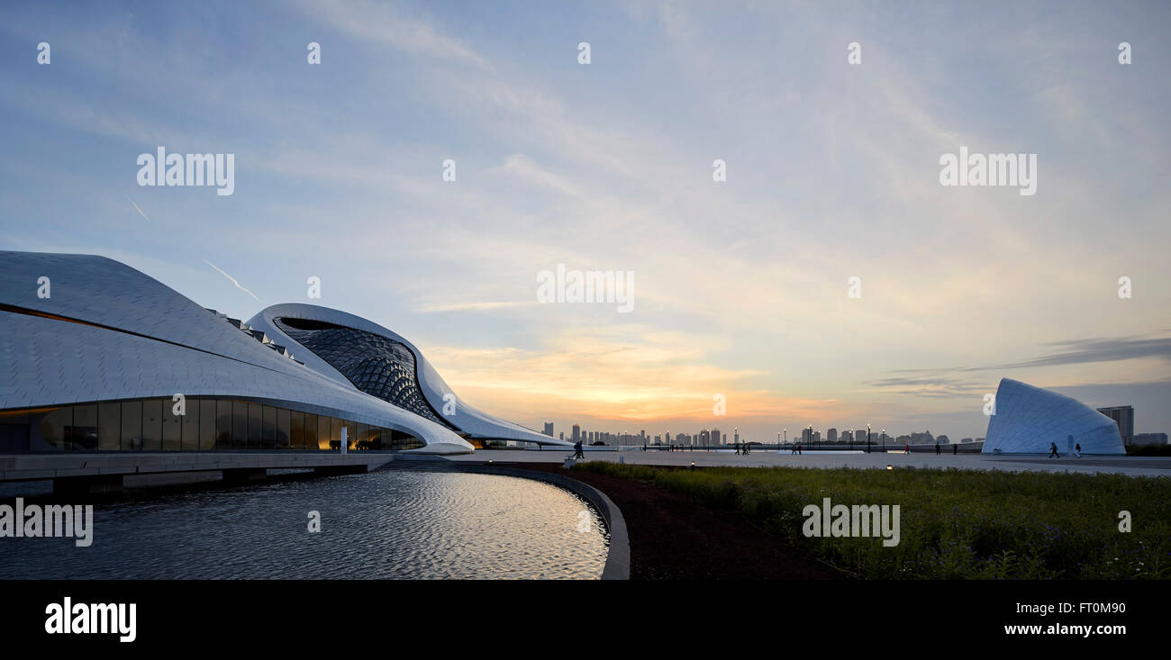 Vista in direzione opera con stagni artificiali e paesaggistici piazza. Harbin Opera House, Harbin, Cina. Architetto: MAD Architects, 2015. Foto Stock