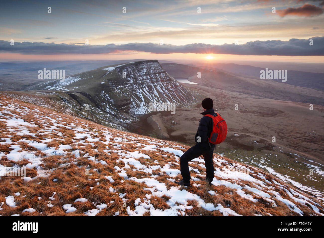 Hillwalker guardando un tramonto in inverno sulla montagna nera. Parco Nazionale di Brecon Beacons. Carmarthenshire. Il Galles. Regno Unito. Foto Stock