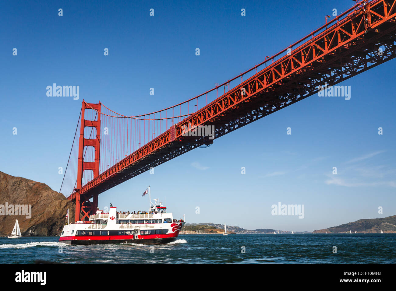 Sole splende sul Golden Gate Bridge con un tour in barca passando sotto di esso Foto Stock