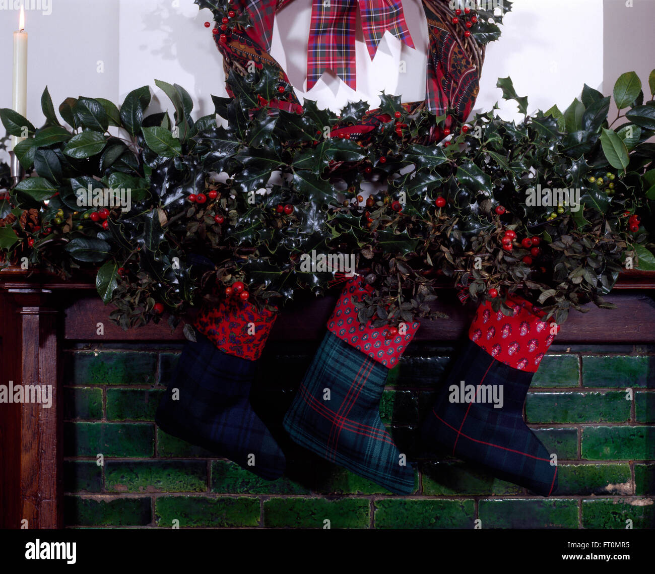 Fatta in Casa di calze di Natale appeso su un mantelpiece con una ghirlanda di agrifoglio fresco e verde fogliame Foto Stock