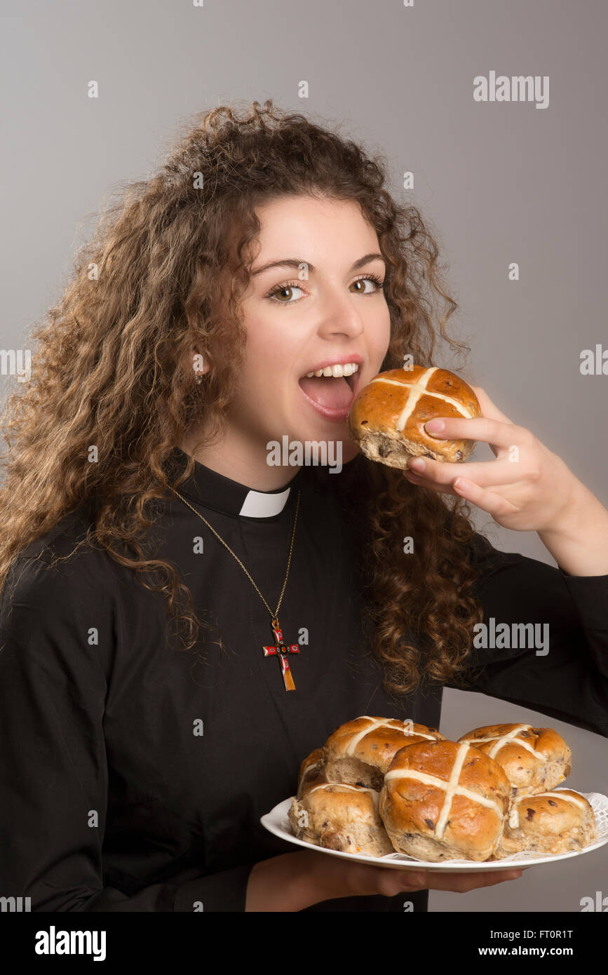 Giovane sacerdote mangiare dolci tradizionali una tradizione al tempo di Pasqua Foto Stock