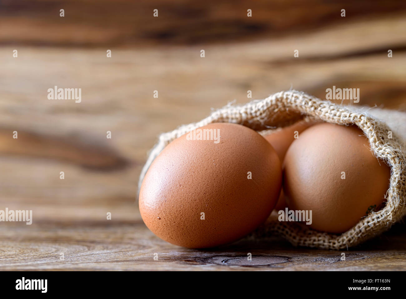 Uova nel sacco di iuta su legno Foto Stock