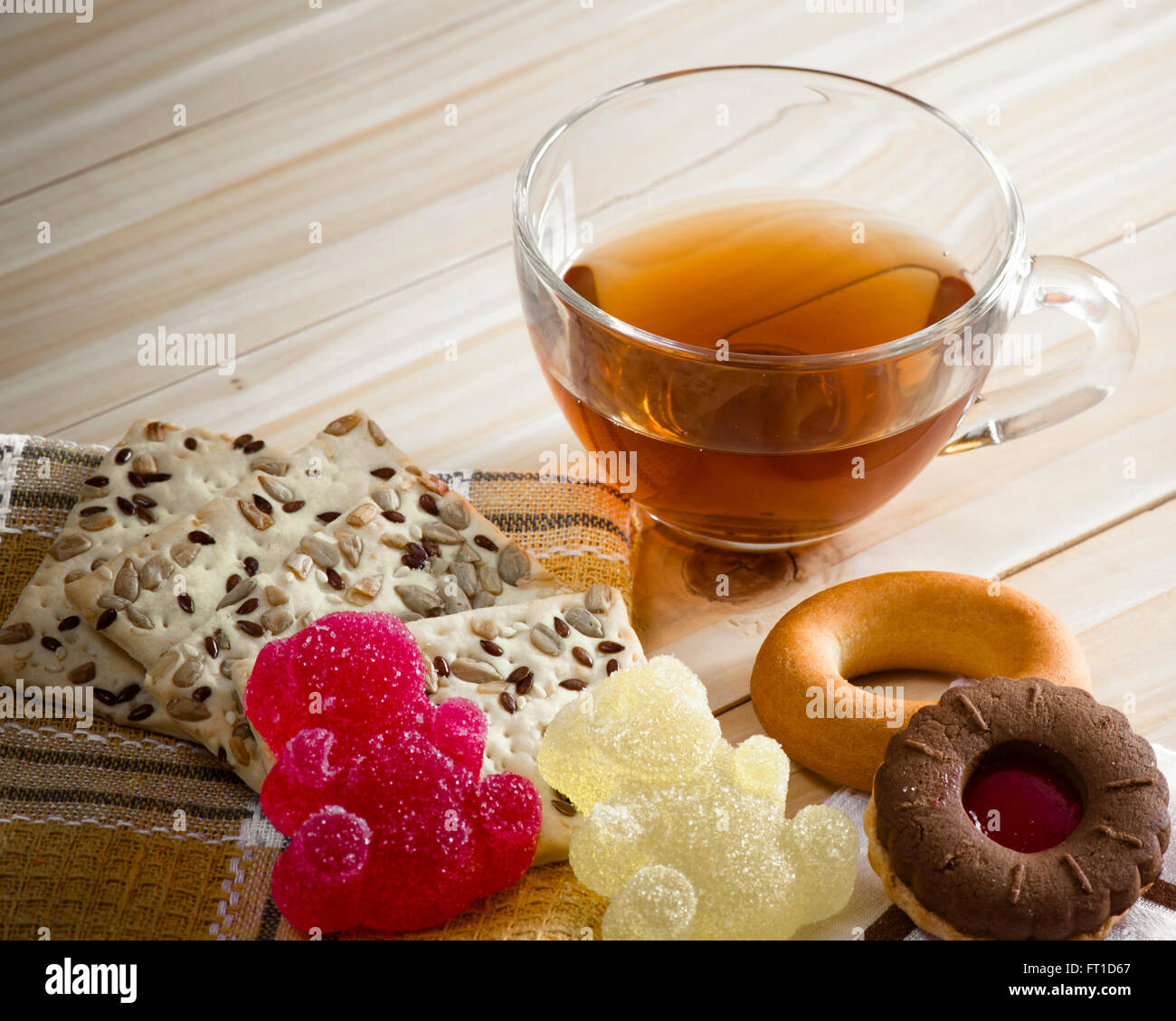 La composizione della bevanda di tè in una grande ciotola e alcuni dolci sul tavolo. I canditi di gelatine di frutta, biscotti di cereali, bagel un Foto Stock