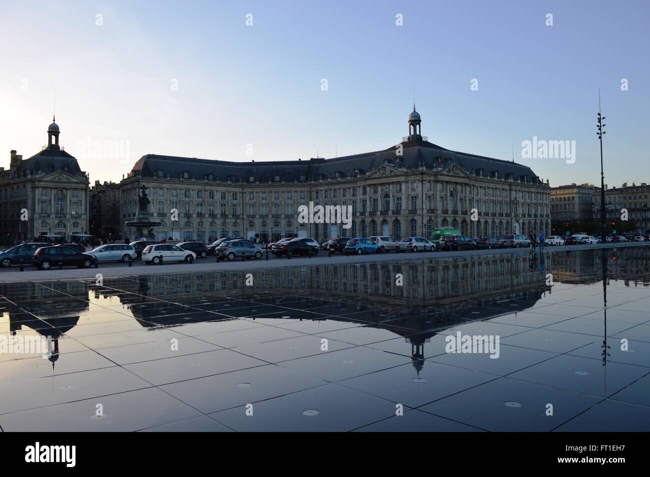 Il Miroir d'Eau a Bordeaux riflettendo edifici, fontana e vetture con cielo blu chiaro Foto Stock