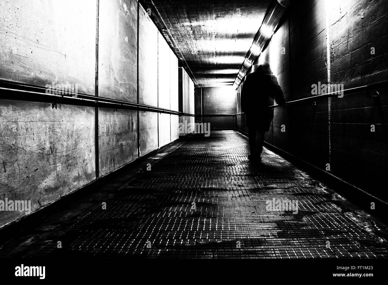 Uomo che cammina da sola in un tunnel Foto Stock